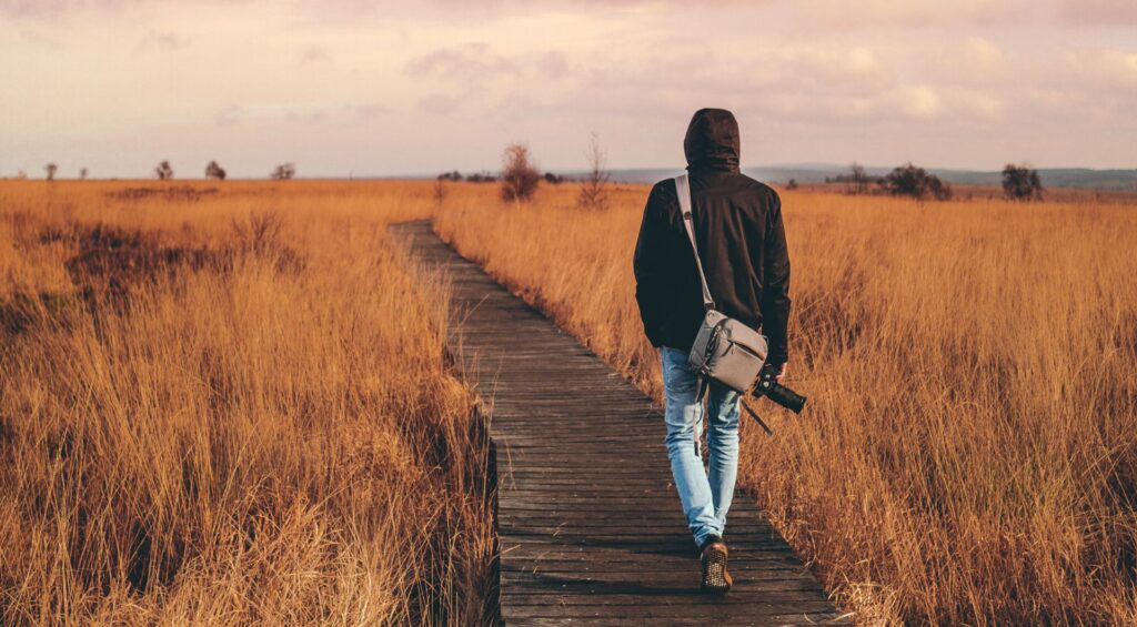 un homme avec un appareil photo sur un chemin en bois